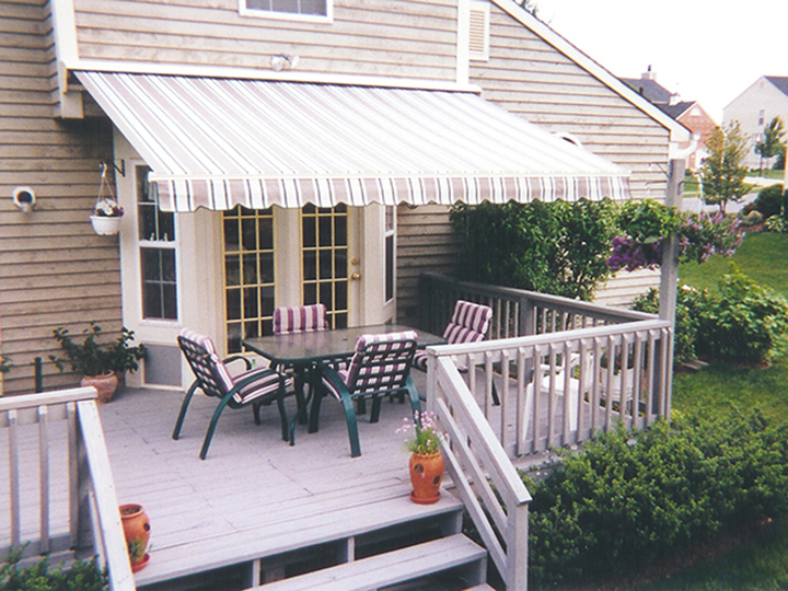 Striped awning over double doors with outdoor chairs and table on a deck